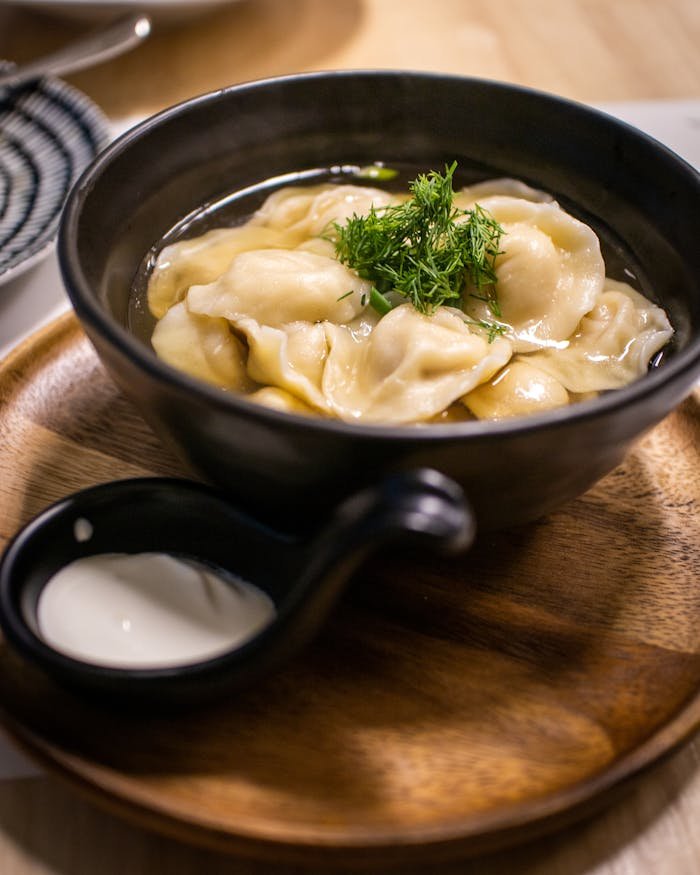 Appetizing dumplings in a black bowl, garnished with herbs, perfect for a traditional meal.