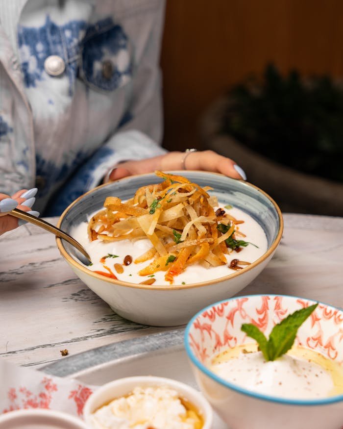 Close-up of a delicious Middle Eastern meal being enjoyed, featuring creamy sauce and fresh herbs.