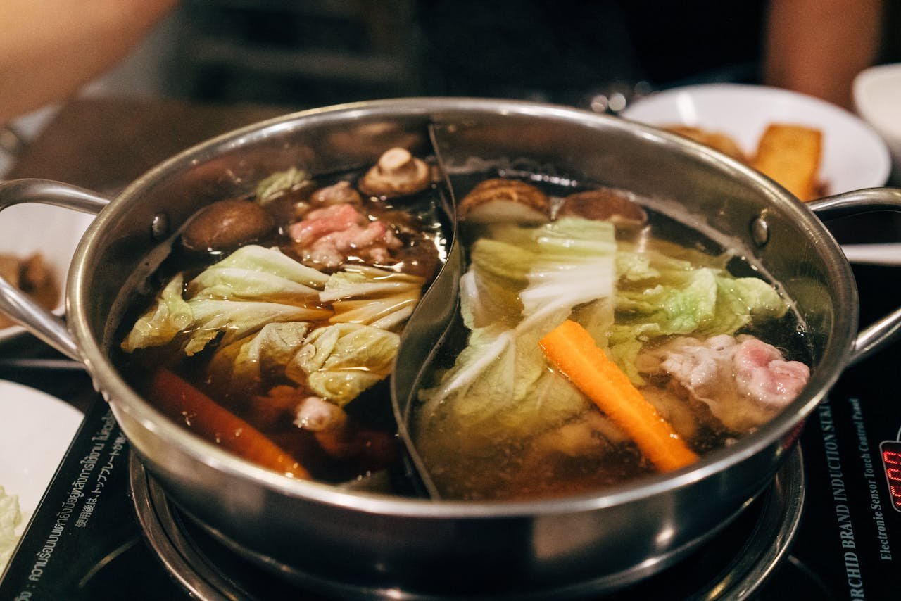 Steaming hot pot filled with meat and vegetables, perfect for culinary photography.