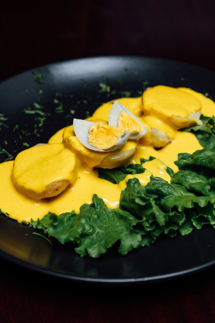 Delicious Peruvian potatoes with creamy huancaína sauce and boiled eggs on lettuce.